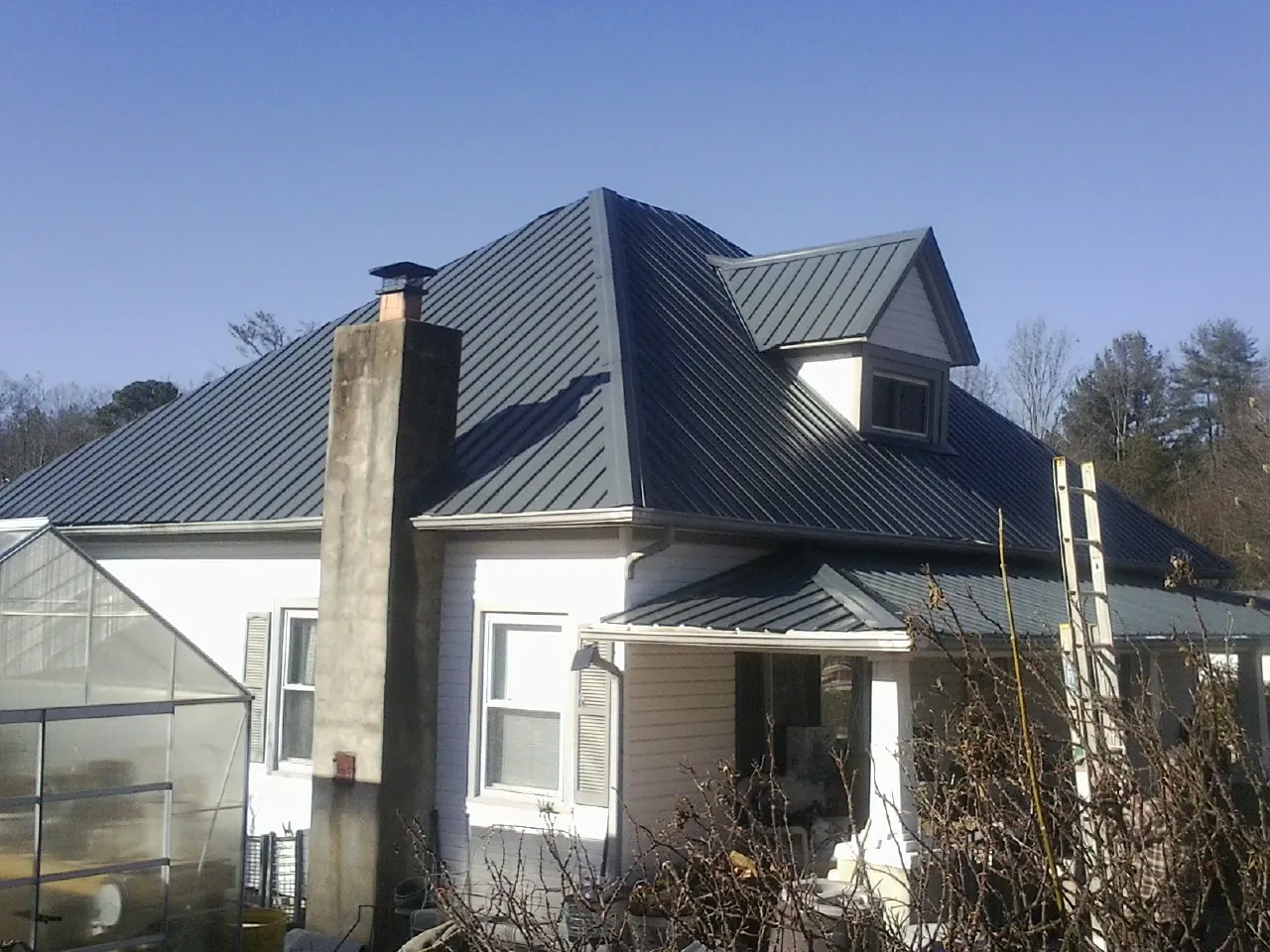 Dark blue standing seam metal roof on a white farmhouse with dormer — Slate & Tile Roof Repair by Roofing Brothers in Reagan