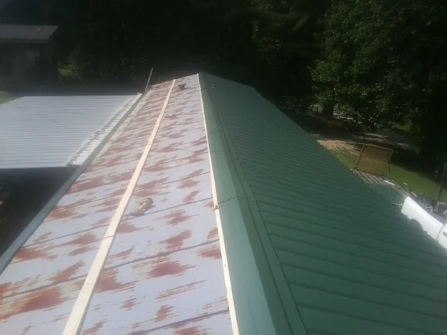 Old rusted panels beside newly installed green metal roofing — Wind Damage Roof Repair by Roofing Brothers in Reagan