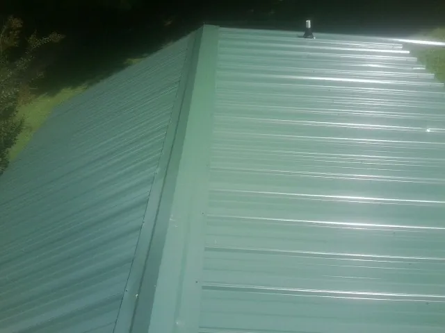 New green metal panels meeting at the ridge of a roof — Flat Roof Repair work by our crew in Reagan