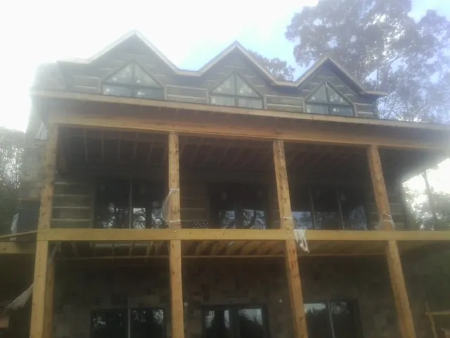 Dormers and porch framing on a large log home under construction — Roof Coating work by our crew in Reagan