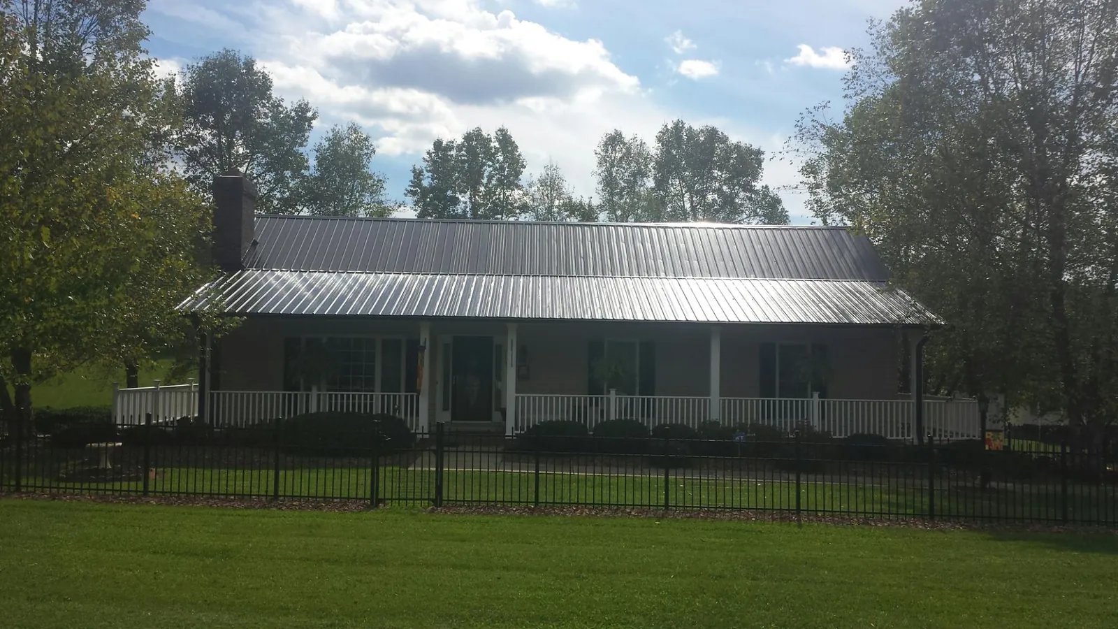 Gray metal roof on a brick ranch with a full width front porch — Gutter Guard Installation work by our crew in Reagan