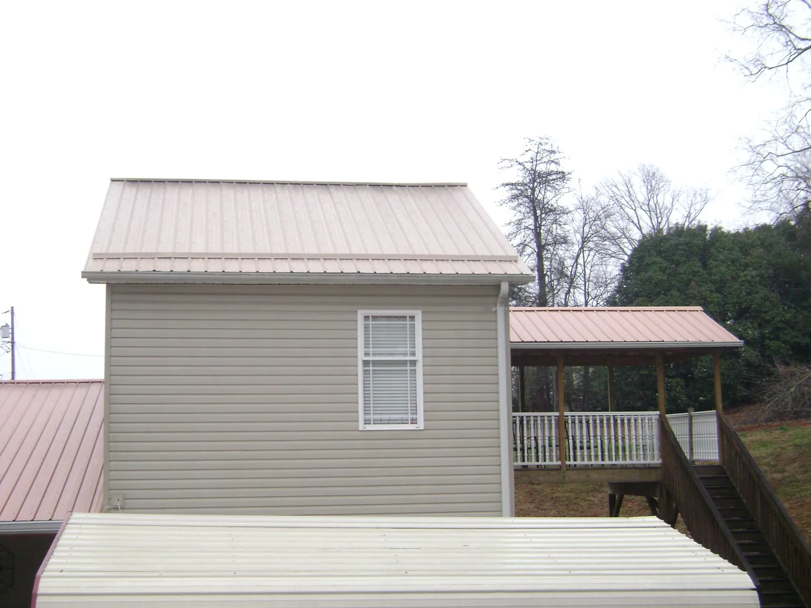 Tan metal roofs on a two story addition and attached porch, from a Roof Replacement job in Reagan
