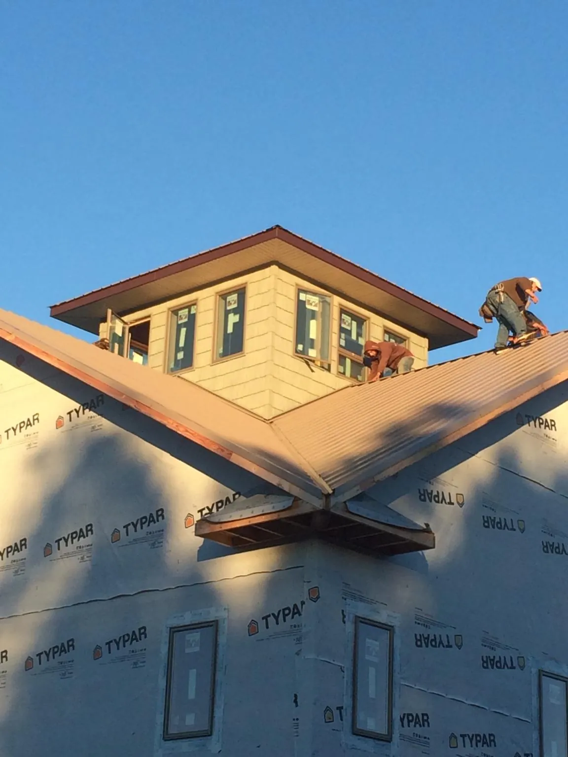 Roofers working around a rooftop cupola on a new metal roof at sunset — Roof Waterproofing in Reagan by Roofing Brothers